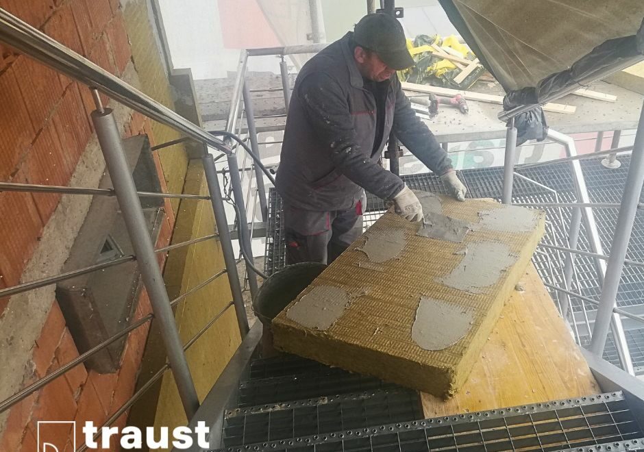 muncitor in constructii care monteaza vata bazaltica pe fatada unei cladiri