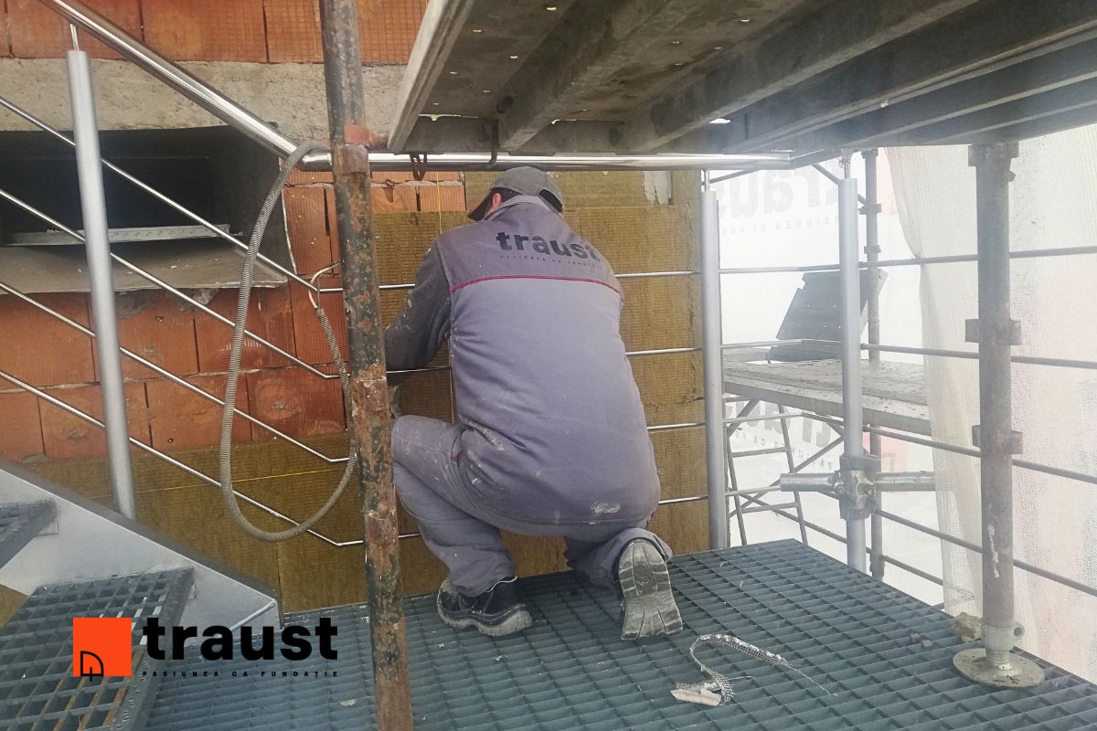 imagine cu muncitor din echipa Traust care monteaza vata bazaltica pe fatada unei cladiri